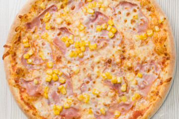 Detial of delicious pizza with ham and corn on the table