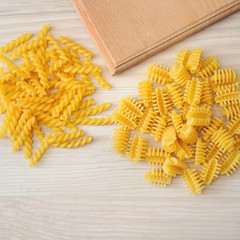 Different types of pasta lying on white table.