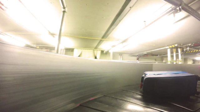 Luggage moving on airport conveyor belt through baggage blinds