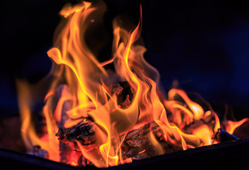 Dance of flames against a dark background, wood burning grill in the open fire.