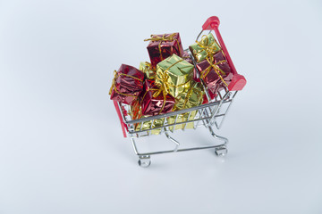 Christmas shopping background compostion of a multiple decoration balls and tiny shopping cart over the wooden surface