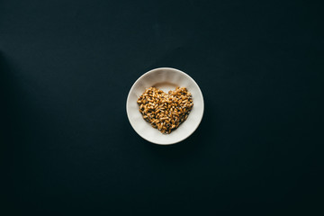 sprouted grains of wheat in shape of heart on white plate. black background with copy space. healthy food concept