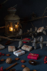 Christmas gifts, rowan, nuts, old lamp on dark surface