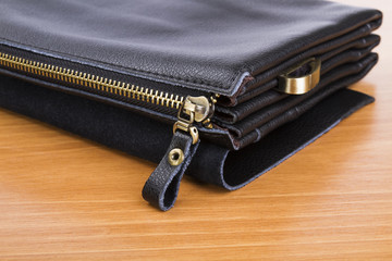 Men's black leather bag on a wooden background