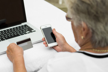 Elderly lady  holding credit card and smartphone.