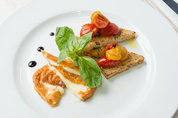 Delicious toast sandwiches with fried cheese, tomatoes, olive oil and basil