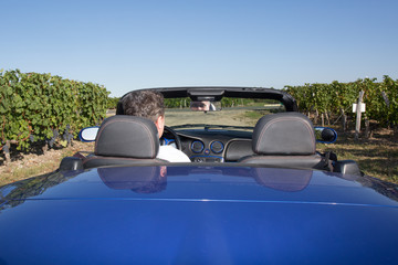 Rear view of a man driving his convertible car