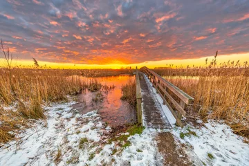 Photo sur Plexiglas Hiver Winter landscape pathway over wooden bridge under orange sunset