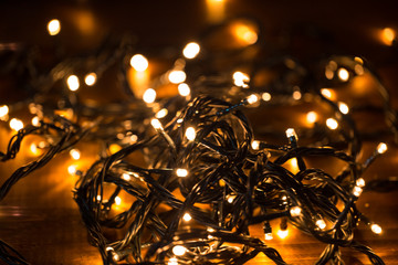 Christmas background with lights on wooden background . Glowing colorful golden Christmas lights in  New Year. © Ievgenii Meyer