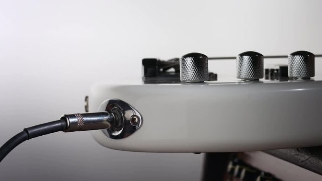 Plug audio cable connector into electric bass guitar jack