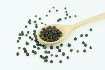 Black pepper in spoon wooden bowl isolated on white background
