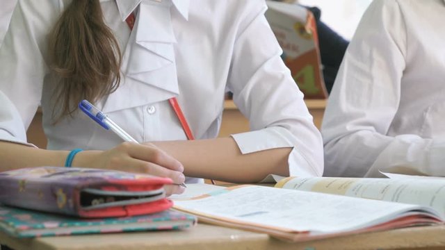 Pupil writes the ext in a copybook using ball pen