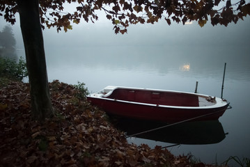 Small boat on the bank of a river in the fog