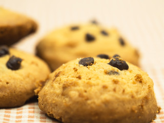 Chocolate cookies on white linen napkin on wooden table. Chocolate chip cookies shot on coffee colored cloth, closeup.