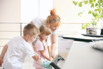 Mother and kids taking biscuits from oven