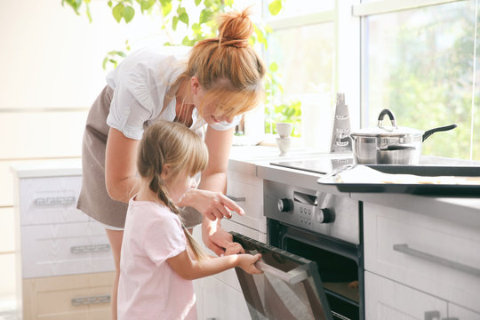 Mother and kids taking biscuits from oven