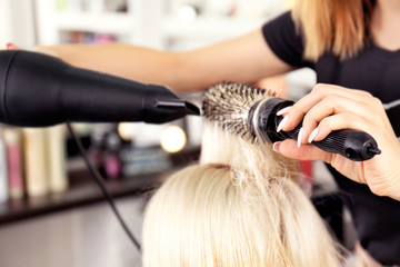 Hairdresser drying blonde's hair at salon