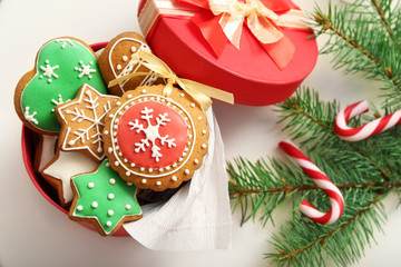 Box with gingerbread cookies, candies and fir tree branch on white table