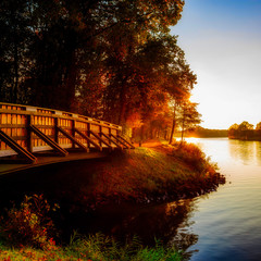 Herbstliche Landschaft an einem Fluss mit Holzbr&uuml;cke bei Sonnenuntergang