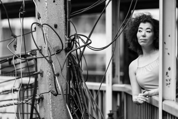 Young Asian woman standing on the overpass in the background of the bundles of wires, black and...