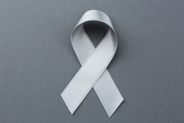Grey ribbon on color background. Brain cancer, diabetes, asthma concept