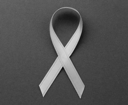 Grey ribbon on color background. Brain cancer, diabetes, asthma concept