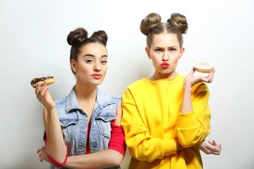 Funny young women with tasty donuts on white background
