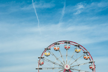 Vintage colorful ferris wheel against a sunny blue sky. Retro fun at a summer fair or a carnival.