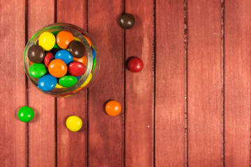 Color candies on red wooden background. Copy space