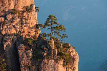 Sunrise from Lion Peak, Huangshan Mountain, China. Early morning sun lights the cliffs below and observation deck at Lion Peak, Yellow Mountains. Mountain range dissolves in the layers of atmosphere.