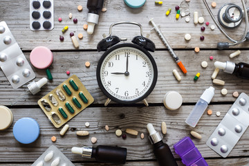 Pills and clock on table, top view