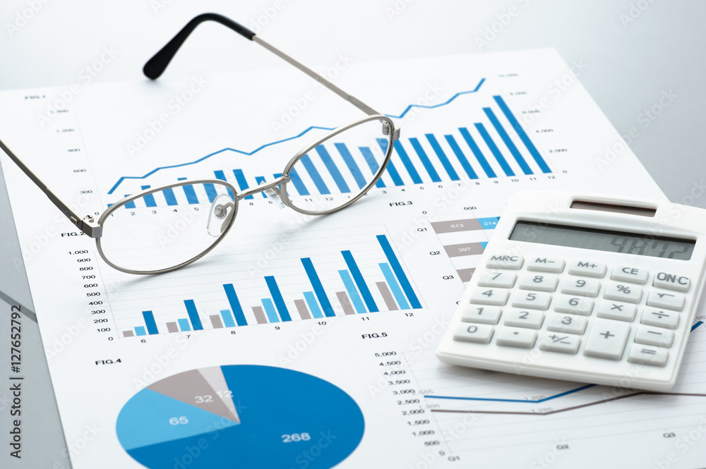 Poster Business document, glasses, and calculator on gray reflection background.
Many graphs and charts. Concept image of data reviewing.
