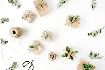 creative arrangement pattern of craft boxes and green branches on white background. flat lay, top view