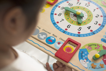 Little kid learning time with clock toy of Montessori.