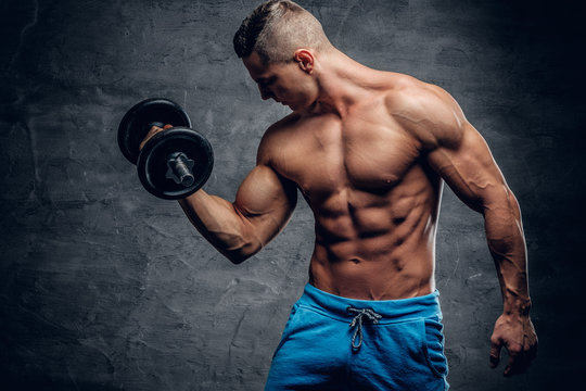 Shirtless muscular male doing workouts with one dumbbell.
