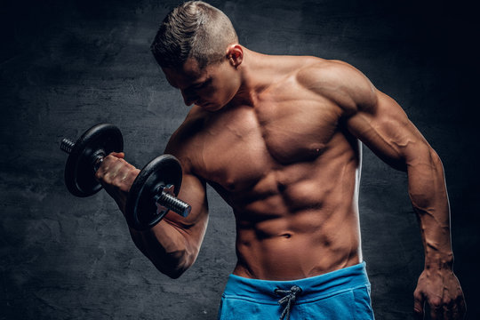 Shirtless muscular male doing workouts with one dumbbell.