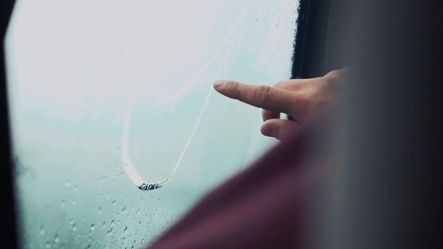 Man draw tongue on window in car by one finger. Rainy weather outside. Drops. Slow motion