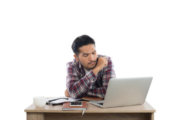Thoughtful young man holding pen looking at notepad while sittin