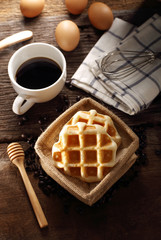 Fresh Waffles and hot coffee for breakfast set with eggs and wood background