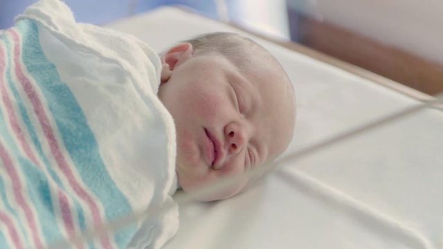 Pan Across Dreaming Newborn Baby Cracking a Smile Sleeping in Hospital Bed