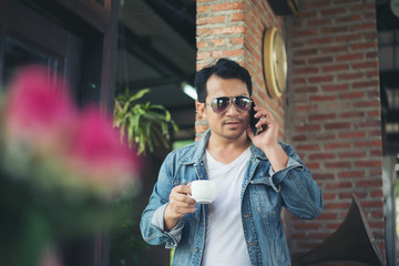 Fototapeta premium Hipster man holding a cup of coffee and walk in the coffee shop,