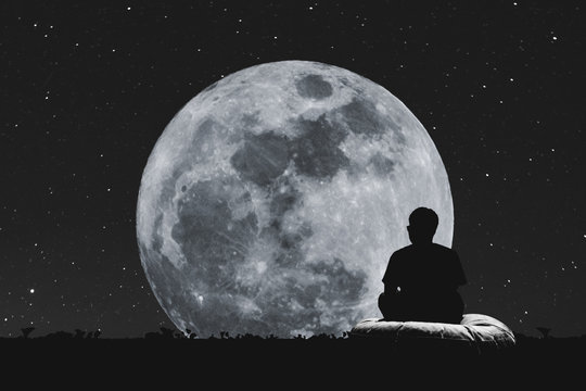 Silhouette A Man Sitting Relaxing Under Full Moon At Night With Stars On The Sky