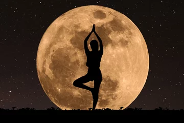 Cercles muraux Pleine lune Silhouette young woman with good shape practicing yoga under full moon at night with stars