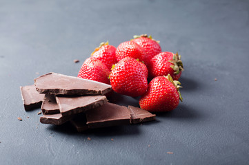 Strawberries with slices of chocolate on a dark background