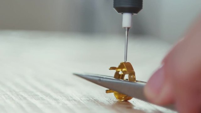 Slow motion. Close-up piece of work, the creation of jewelry. A tool for creating jewelry - jewelry drill. Master keeps tweezers for faceting stones.