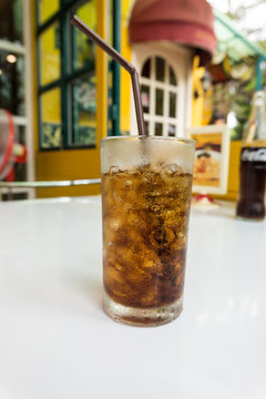 glass of sweetened cola, carbonated soft drink and ice on table