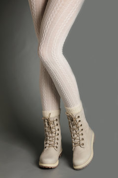 Female legs in white tights and bright winter boots.