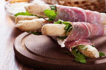 Italian grissini with ham prosciutto, mozzarella and arugula