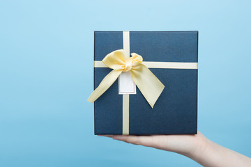 Female hand holding gift box over color background