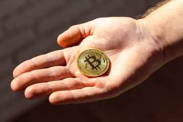 Golden Bitcoin in a man's hand